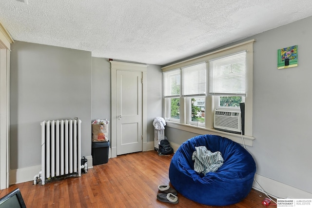 115 N 38th Ave, Omaha, NE 68131 - living area featuring radiator, wood finished floors, a textured ceiling, and cooling unit