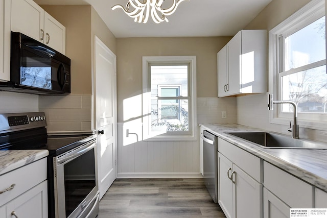 3948 N 54th St, Omaha, NE 68104 - kitchen with appliances with stainless steel finishes, a sink, a chandelier, light wood finished floors, and white cabinets