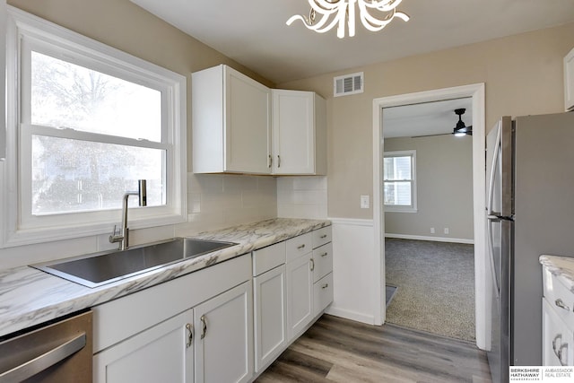 3948 N 54th St, Omaha, NE 68104 - kitchen with appliances with stainless steel finishes, a sink, a chandelier, white cabinets, and tasteful backsplash