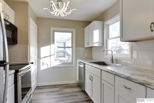 3948 N 54th St, Omaha, NE 68104 - kitchen featuring a sink, stainless steel appliances, light wood-type flooring, a chandelier, and a wainscoted wall
