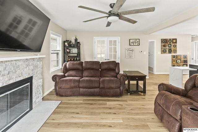2026 N Park Ave, Fremont, NE 68025 - living room featuring ceiling fan, light wood-style flooring, a stone fireplace, and baseboards