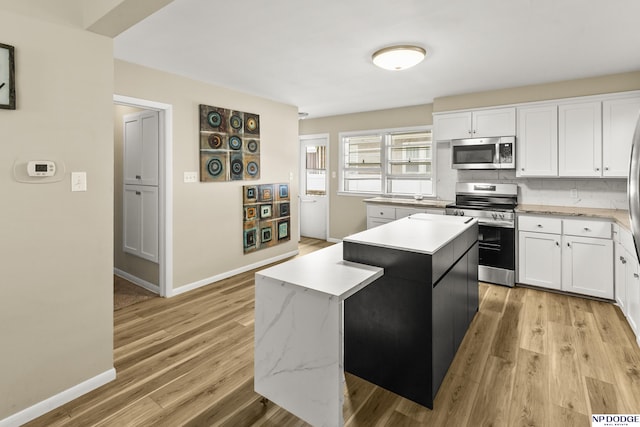 2026 N Park Ave, Fremont, NE 68025 - kitchen with stainless steel appliances, a center island, white cabinets, light wood-type flooring, and baseboards