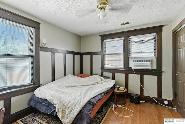 121 N 38th Ave, Omaha, NE 68131 - bedroom with cooling unit, wood finished floors, multiple windows, a textured ceiling, and ceiling fan