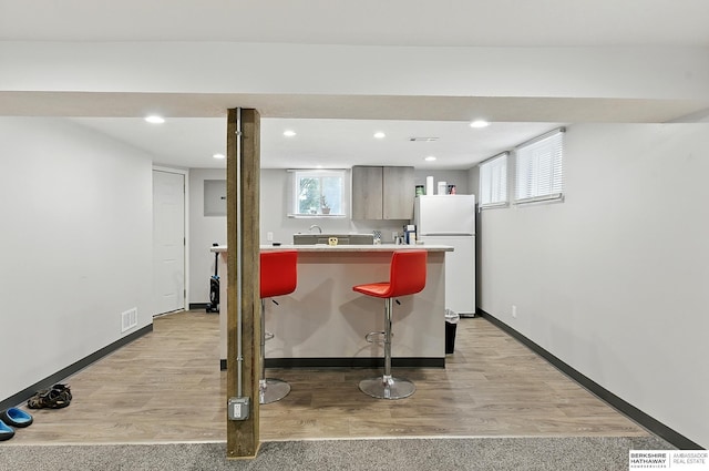 121 N 38th Ave, Omaha, NE 68131 - kitchen featuring freestanding refrigerator, light wood finished floors, light countertops, a kitchen bar, and recessed lighting