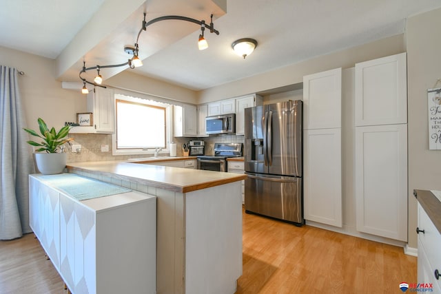 2430 Jameson St S, Lincoln, NE 68512 - kitchen with stainless steel appliances, a peninsula, backsplash, and light wood-style floors
