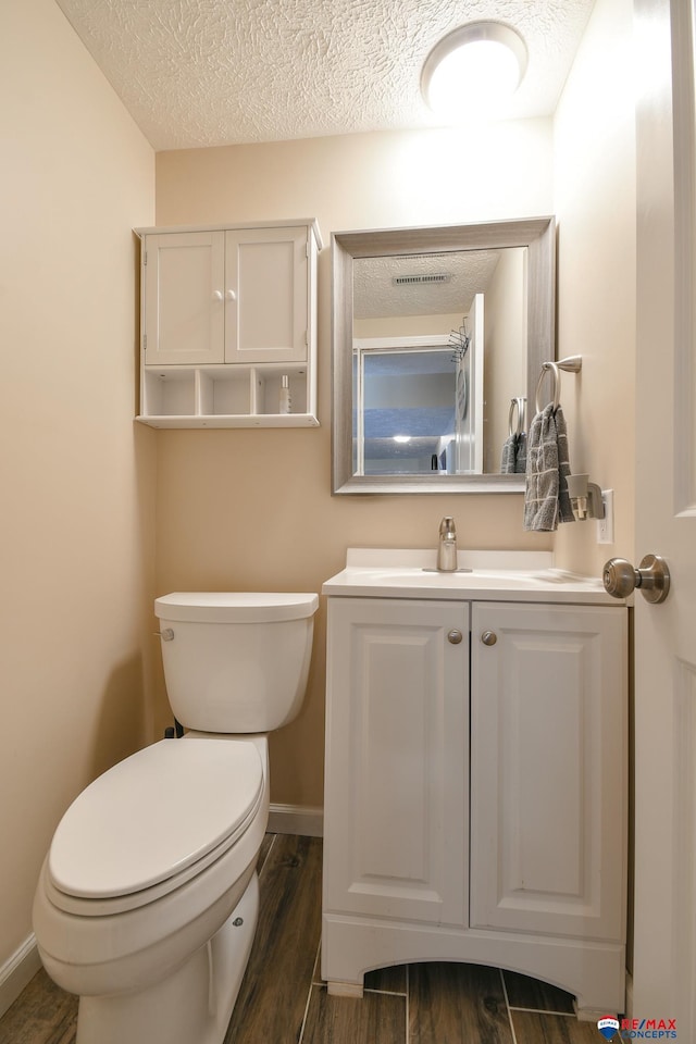 2430 Jameson St S, Lincoln, NE 68512 - bathroom with toilet, vanity, a textured ceiling, wood finished floors, and baseboards