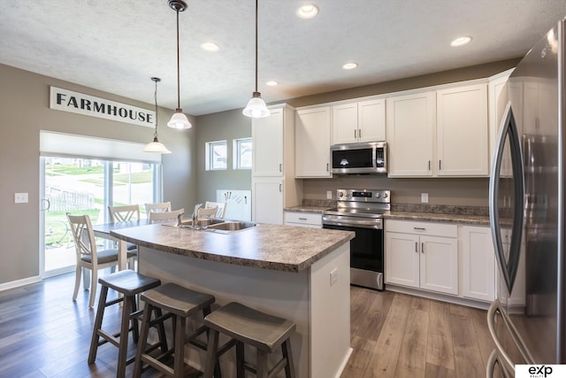 5614 N 177th St, Omaha, NE 68116 - kitchen with appliances with stainless steel finishes, a sink, wood finished floors, white cabinets, and an island with sink