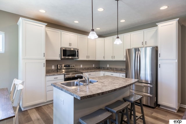 5614 N 177th St, Omaha, NE 68116 - kitchen featuring appliances with stainless steel finishes, a sink, wood finished floors, a kitchen island with sink, and recessed lighting