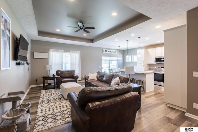 5614 N 177th St, Omaha, NE 68116 - living area with a raised ceiling, light wood-style floors, ceiling fan, baseboards, and recessed lighting