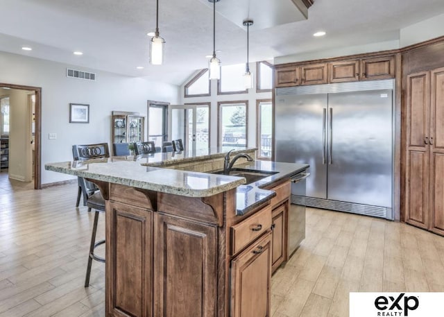 11103 S 173rd St, Omaha, NE 68136 - kitchen with stainless steel appliances, a kitchen bar, light wood-style flooring, stone counters, and pendant lighting