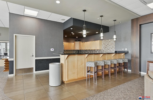 3201 Dodge Ct Unit 5412, Omaha, NE 68131 - kitchen featuring tile patterned flooring, light brown cabinets, a kitchen bar, baseboards, and recessed lighting