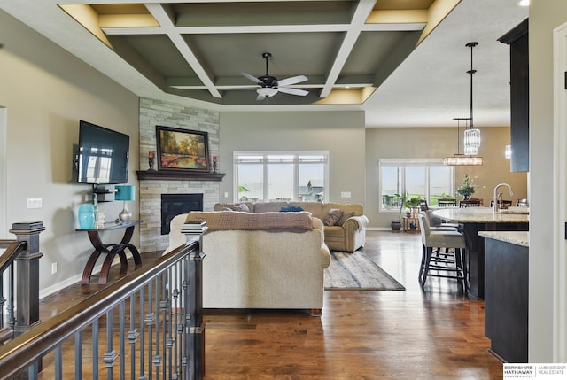235 N 10th Ave, Springfield, NE 68059 - living room with ceiling fan, a stone fireplace, coffered ceiling, baseboards, and dark wood-style floors
