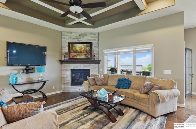 235 N 10th Ave, Springfield, NE 68059 - living room with wood finished floors, ceiling fan, a stone fireplace, baseboards, and a raised ceiling
