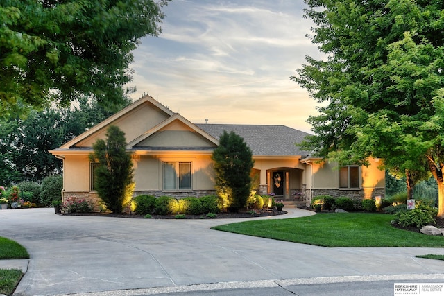 19252 Shirley St, Omaha, NE 68130 - view of front of home with stone siding, stucco siding, a front yard, and driveway