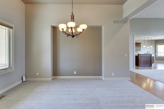 19252 Shirley St, Omaha, NE 68130 - empty room with a chandelier, light colored carpet, baseboards, and light wood-style flooring
