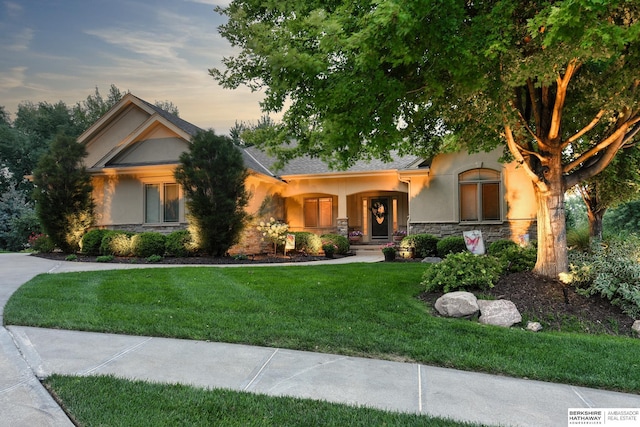 19252 Shirley St, Omaha, NE 68130 - view of front of property with stone siding, stucco siding, a front lawn, and a porch