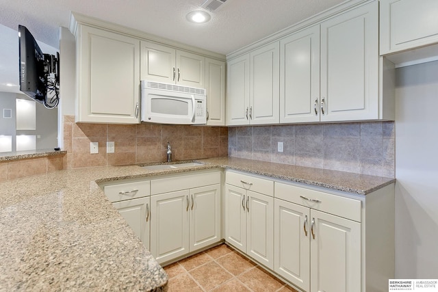 19252 Shirley St, Omaha, NE 68130 - kitchen featuring white microwave, a sink, light stone counters, decorative backsplash, and a textured ceiling