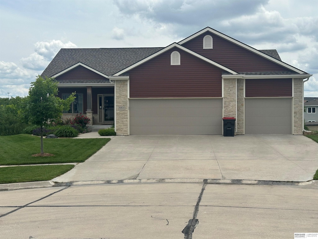 6901 N 13th Cir, Lincoln, NE 68521 - craftsman-style house featuring stone siding, an attached garage, a front lawn, concrete driveway, and roof with shingles