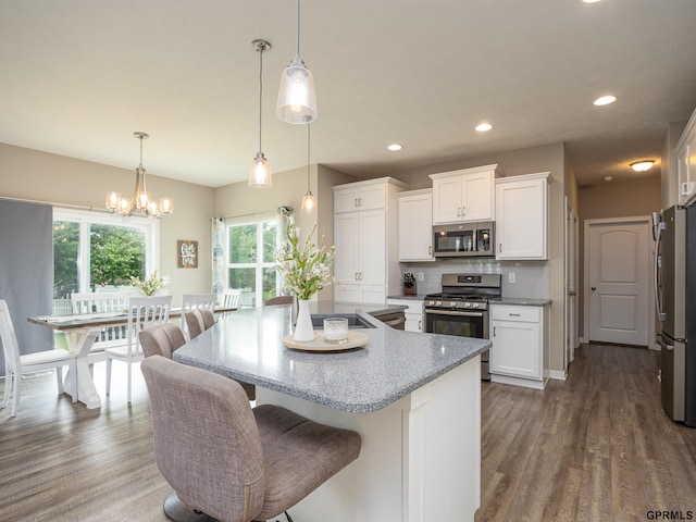 15218 Vane St, Bennington, NE 68007 - kitchen featuring appliances with stainless steel finishes, white cabinets, wood finished floors, light stone counters, and recessed lighting