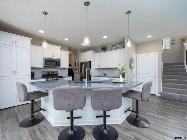 15218 Vane St, Bennington, NE 68007 - kitchen with appliances with stainless steel finishes, dark wood-style floors, white cabinetry, a breakfast bar area, and recessed lighting
