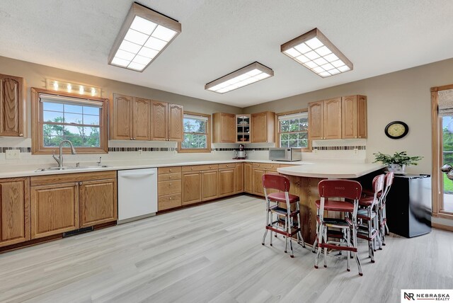 7105 W Davey Rd, Raymond, NE 68428 - kitchen with white appliances, a sink, a kitchen bar, and light wood-style flooring