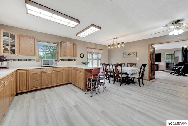 7105 W Davey Rd, Raymond, NE 68428 - kitchen featuring white microwave, a peninsula, light wood-style floors, glass insert cabinets, and light countertops