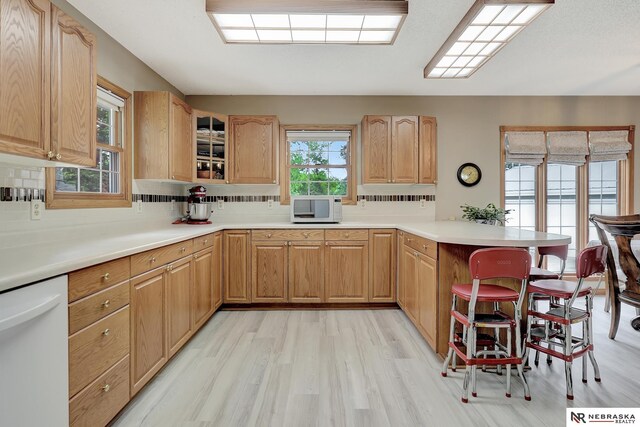 7105 W Davey Rd, Raymond, NE 68428 - kitchen featuring white appliances, a peninsula, a kitchen bar, light wood-style floors, and glass insert cabinets