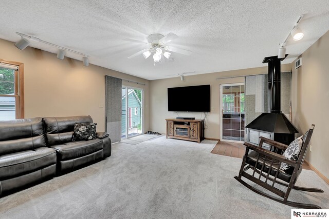 7105 W Davey Rd, Raymond, NE 68428 - living area featuring rail lighting, a wood stove, carpet, a ceiling fan, and a textured ceiling