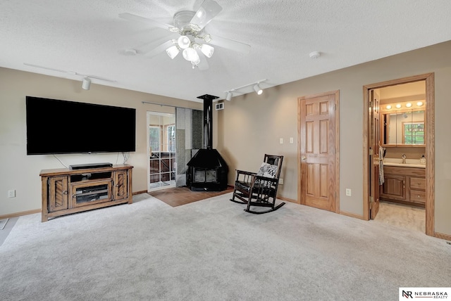 7105 W Davey Rd, Raymond, NE 68428 - living area featuring rail lighting, a wood stove, carpet, a textured ceiling, and ceiling fan