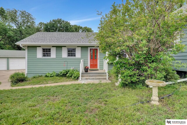 7105 W Davey Rd, Raymond, NE 68428 - view of front of house featuring a front yard, an outdoor structure, a detached garage, and roof with shingles