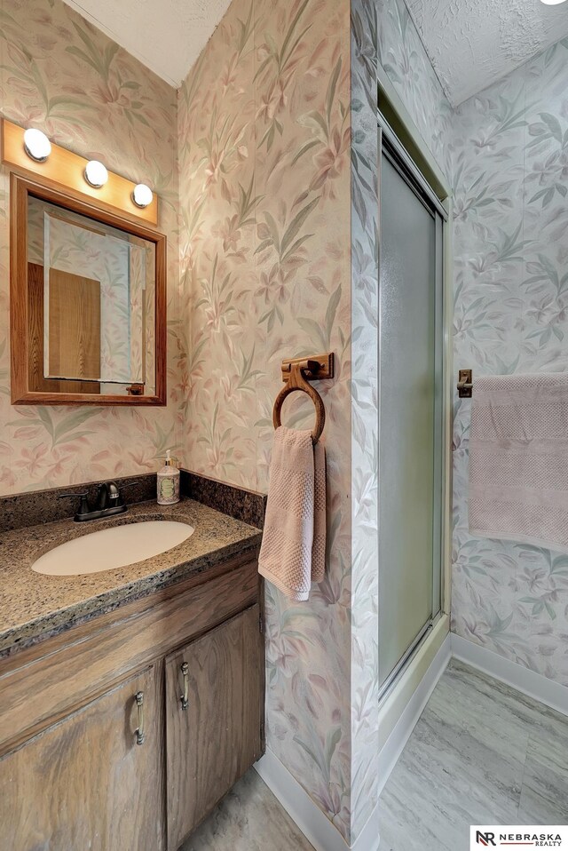 7105 W Davey Rd, Raymond, NE 68428 - bathroom with wallpapered walls, vanity, an enclosed shower, and baseboards