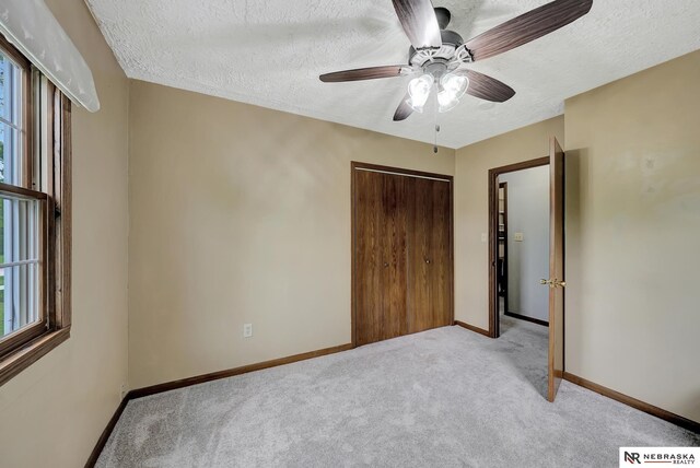 7105 W Davey Rd, Raymond, NE 68428 - unfurnished bedroom with carpet, a textured ceiling, a closet, baseboards, and a ceiling fan