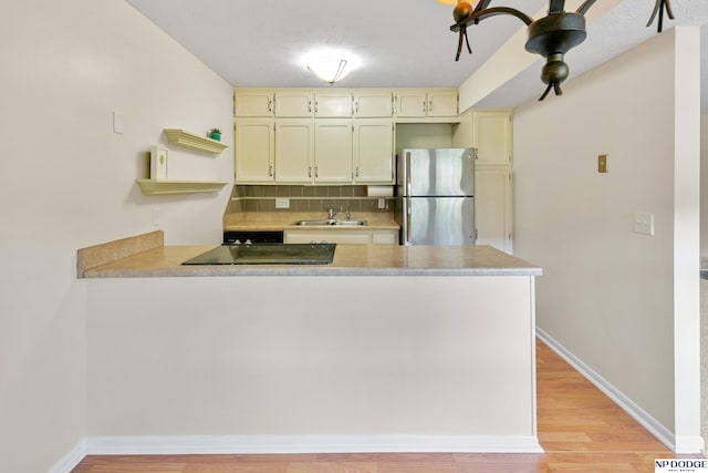 12726 Gail Plz Unit 107, Omaha, NE 68137 - kitchen featuring freestanding refrigerator, a peninsula, a sink, and light countertops