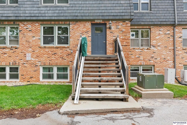 12726 Gail Plz Unit 107, Omaha, NE 68137 - doorway to property featuring mansard roof, brick siding, and a yard