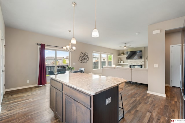 7775 N 149th St, Bennington, NE 68007 - kitchen featuring ceiling fan, a breakfast bar, a stone fireplace, dark wood-style flooring, and hanging light fixtures