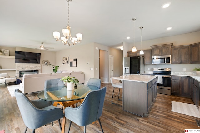 7775 N 149th St, Bennington, NE 68007 - dining space featuring a ceiling fan, a fireplace, a chandelier, dark wood finished floors, and recessed lighting