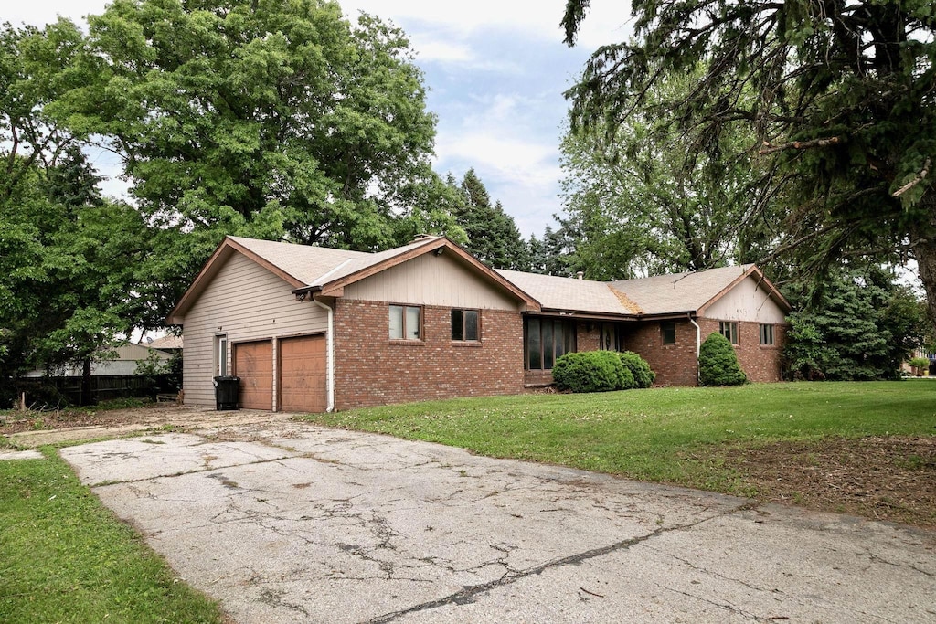 5130 O St, Omaha, NE 68117 - ranch-style house featuring brick siding, an attached garage, a front lawn, and driveway