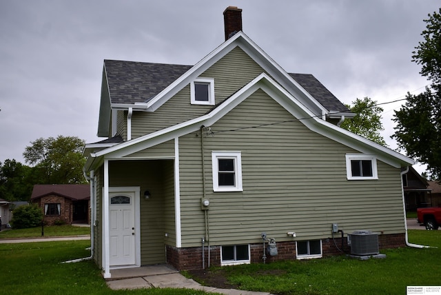 116 8th St, Scribner, NE 68057 - back of house featuring central air condition unit, a yard, a chimney, and a shingled roof