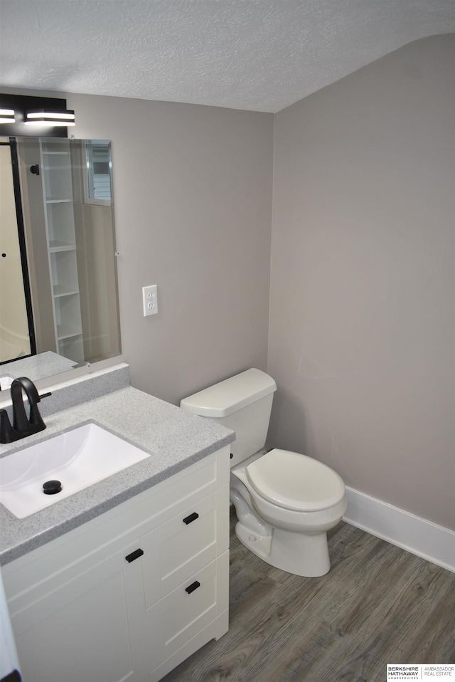 116 8th St, Scribner, NE 68057 - bathroom with wood finished floors, vanity, toilet, a textured ceiling, and baseboards