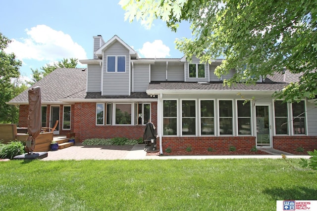 2600 Evergreen Cir, Beatrice, NE 68310 - view of front of home with brick siding, a patio area, a front lawn, and a chimney