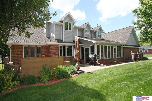 2600 Evergreen Cir, Beatrice, NE 68310 - back of property with brick siding, a yard, a sunroom, and a shingled roof