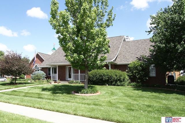 2600 Evergreen Cir, Beatrice, NE 68310 - view of front of house with brick siding, a front lawn, a shingled roof, and covered porch