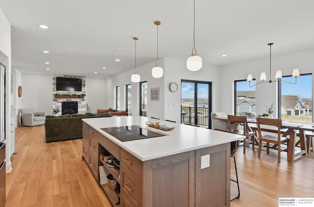 11065 N 171st St, Bennington, NE 68007 - kitchen with black electric stovetop, a stone fireplace, light wood-style flooring, oven, and recessed lighting