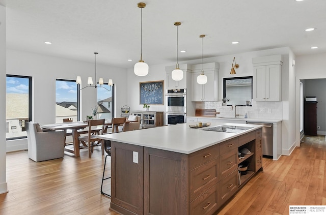 11065 N 171st St, Bennington, NE 68007 - kitchen featuring stainless steel appliances, light countertops, light wood-style floors, tasteful backsplash, and white cabinets
