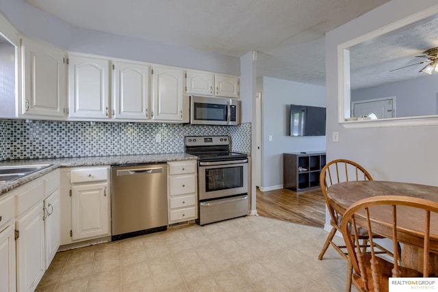 12180 Pedersen Dr, Omaha, NE 68144 - kitchen with appliances with stainless steel finishes, backsplash, white cabinets, and light stone countertops