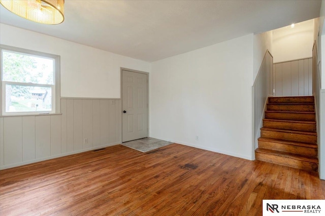 8261 Stephanie Ln, Bellevue, NE 68147 - unfurnished room featuring wood finished floors, stairway, and wainscoting