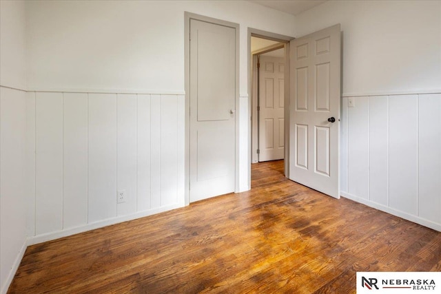 8261 Stephanie Ln, Bellevue, NE 68147 - unfurnished bedroom with a decorative wall, wood finished floors, and a wainscoted wall