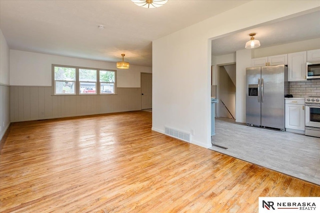 8261 Stephanie Ln, Bellevue, NE 68147 - kitchen with stainless steel appliances, light wood-style floors, white cabinetry, a wainscoted wall, and light countertops