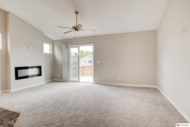 7707 N 88th St, Omaha, NE 68122 - unfurnished living room with ceiling fan, a glass covered fireplace, carpet, vaulted ceiling, and baseboards