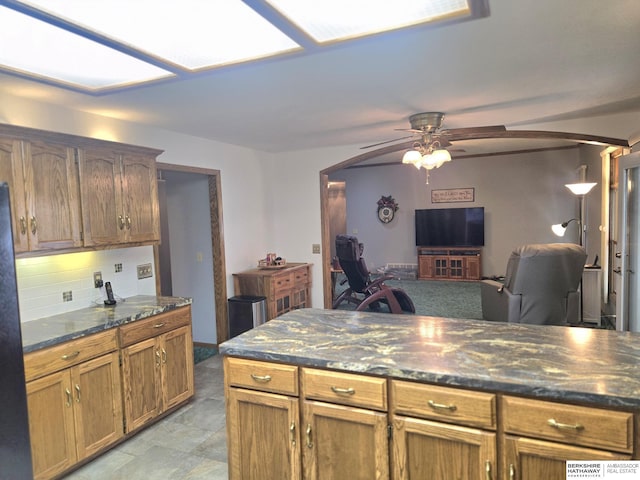 2205 Hidden Canyon Rd, Plattsmouth, NE 68048 - kitchen featuring tasteful backsplash, ceiling fan, arched walkways, open floor plan, and dark stone counters
